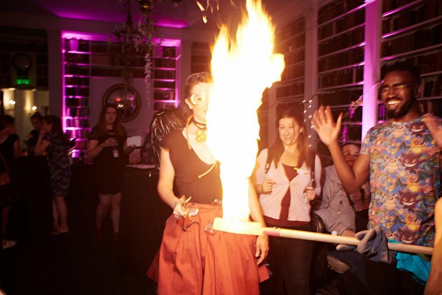 a firey explosion in the centre of a small plate being held by one of our science demonstrators with a crowd looking on