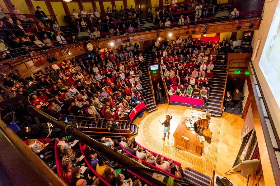 theatre full of guests with a woman presenting from the front