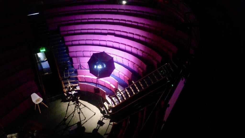 image of the theatre in darkness with just a section of the magenta seats lit up